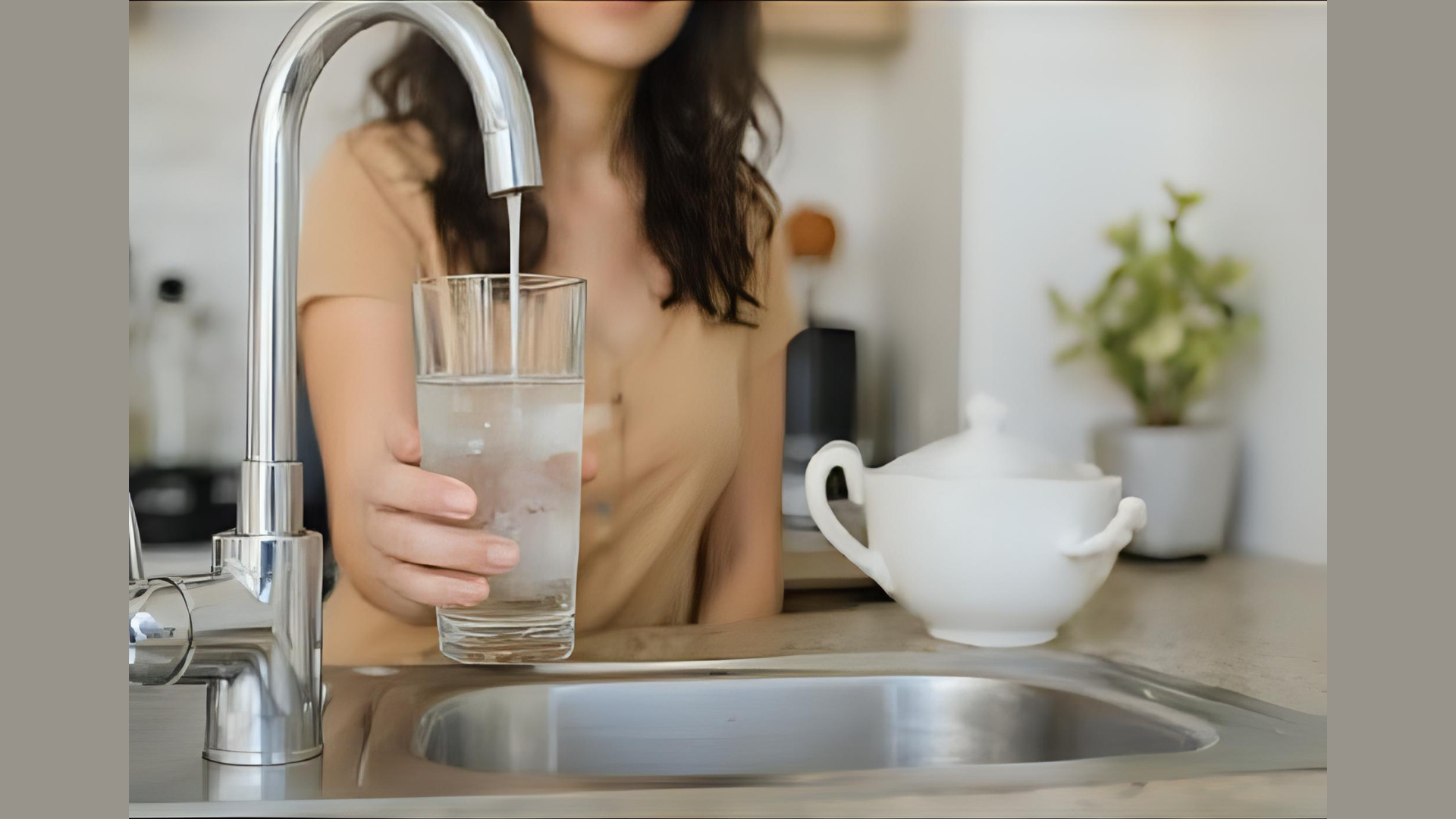 Woman filling a glass with clean filtered water at her kitchen sink